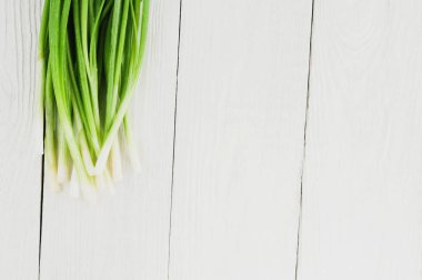 Eski beyaz rustik ahşap masa üzerinde yeşil taze soğan yığını