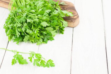 Kahverengi kesme tahtası ve eski ahşap beyaz rustik plakalar yanında maydanoz bir dal yeşil taze çiğ maydanoz yığını