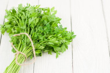 Eski beyaz ahşap rustik plakalar üzerinde kahverengi ip ile bağlı yeşil çiğ taze maydanoz Demet