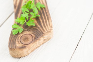 Eski beyaz ahşap rustik plakalar üzerinde kahverengi kesme tahtası maydanoz bir yeşil taze dal