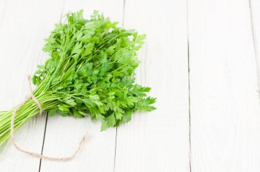 Eski beyaz ahşap rustik plakalar üzerinde kahverengi ip ile bağlı yeşil çiğ taze maydanoz Demet