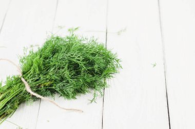 Eski ahşap beyaz rustik plakalar üzerinde kahverengi halat bağlı yeşil taze ham dereotu yığını