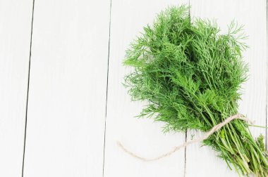 Eski ahşap beyaz rustik plakalar üzerinde kahverengi halat bağlı yeşil taze ham dereotu yığını