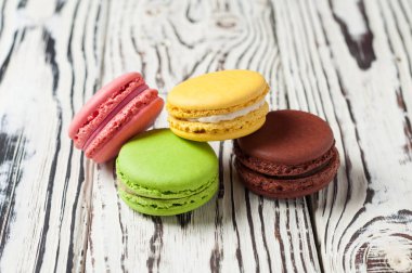 Çeşitli renklerde yığın ve eski beyaz ahşap tahtalar üzerinde fransız kurabiye macaroons tadı