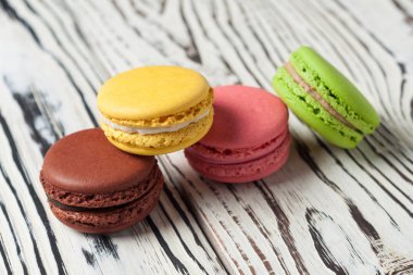 Çeşitli renklerde yığın ve eski beyaz ahşap tahtalar üzerinde fransız kurabiye macaroons tadı
