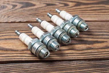 Atölyede eski kahverengi ahşap masa üzerinde motor için beş bujiler Satır