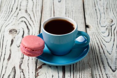 Eski yıpranmış rustik beyaz masada tatlı pembe macaroon yakın sıcak siyah kahve tam seramik fincan. Kopyalama alanı