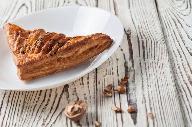 Dağınık Yunan fındık yakın seramik plaka tohum ile üçgen şeklinde bir bütün ekmek eski yıpranmış Beyaz ahşap masada yatıyor