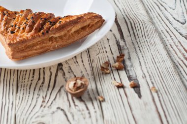 Dağınık Yunan fındık yakın seramik plaka tohum ile üçgen şeklinde bir bütün ekmek eski yıpranmış Beyaz ahşap masada yatıyor