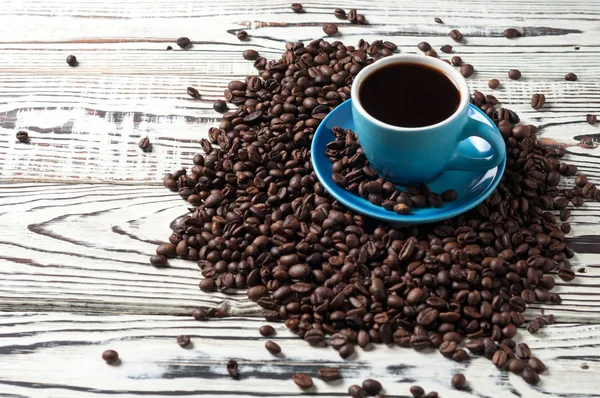 Eski rustik beyaz ahşap masada dağınık kızarmış fasulye çok yakın siyah sıcak kahve tam mavi seramik fincan. Metin için boşluk Kopyala