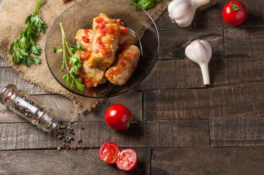 Çuvallama ve rustik ahşap masa üzerinde sebze yakın siyah cam tabakta pirinç ve et dolu domates soslu haşlanmış lahana rulo bir porsiyon