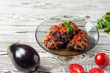 Taze domates ve maydanoz yakın koyu cam kase içinde eritilmiş peynir ve sos ile pişmiş patlıcan rustik beyaz ahşap masa üzerinde yatıyor. Kopyalama alanı