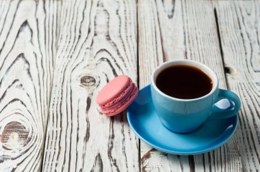 Eski yıpranmış rustik beyaz masada tatlı pembe macaroon yakın sıcak siyah kahve tam seramik fincan. Kopyalama alanı