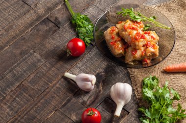 Çuvallama ve rustik ahşap masa üzerinde sebze yakın siyah cam tabakta pirinç ve et dolu domates soslu haşlanmış lahana rulo bir porsiyon