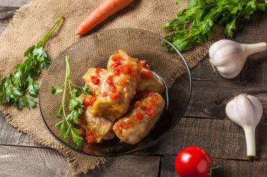 Çuvallama ve rustik ahşap masa üzerinde sebze yakın siyah cam tabakta pirinç ve et dolu domates soslu haşlanmış lahana rulo bir porsiyon