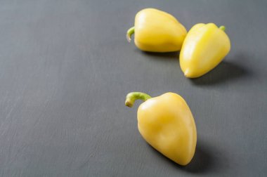 Dağınık bütün taze olgun biber koyu çimento masada yatıyor. Metin için alan kopyalama