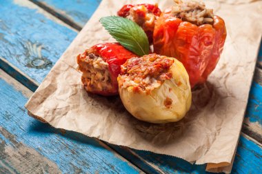 Nane yaprağı ile biber dolması yığını buruşturulmuş kağıt ve eski mavi rustik ahşap masa üzerinde yatıyor