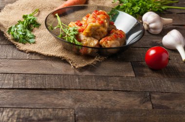 Çuvallama ve rustik ahşap masa üzerinde sebze yakın siyah cam tabakta pirinç ve et dolu domates soslu haşlanmış lahana rulo bir porsiyon