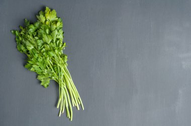 Bütün taze olgun maydanoz bir demet koyu çimento masada yatıyor