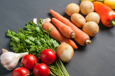 Farklı taze bütün olgun sebze seti koyu beton masa üzerinde yatıyor