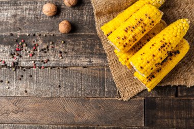 Bütün yunan fındık yakınında kızarmış mısır koçan yığını, dağınık biber çuval bezi ve eski kahverengi rustik ahşap masa yatıyor. Kopyalama alanı