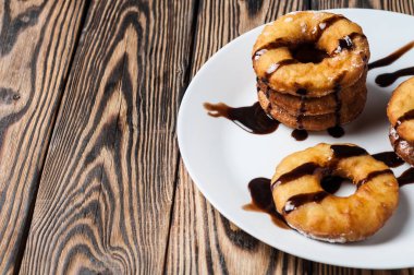 Çikolata krema süslenmiş birçok ev yapımı pişmiş çörekler beyaz seramik plaka ve eski rustik ahşap masa yatıyor