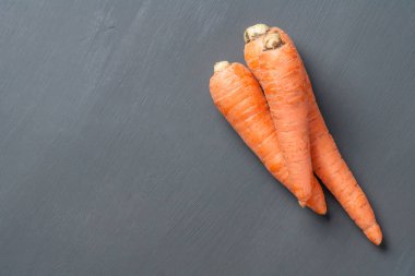 Bütün taze olgun havuç yığını koyu çimento masada yatıyor. Metin için alan kopyalama