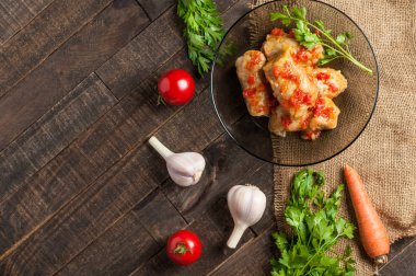 Çuvallama ve rustik ahşap masa üzerinde sebze yakın siyah cam tabakta pirinç ve et dolu domates soslu haşlanmış lahana rulo bir porsiyon