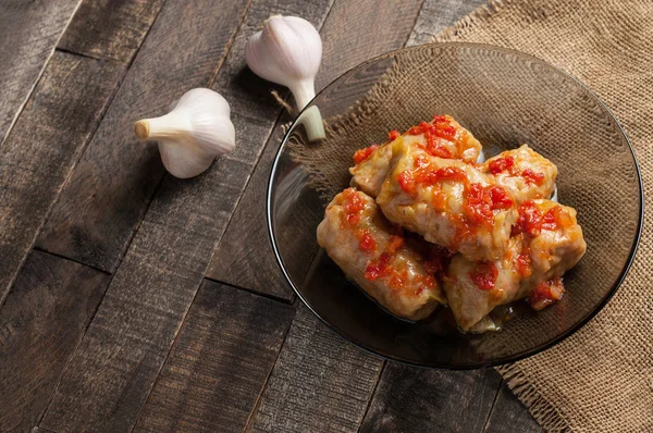 양배추 부분과 고기로 채워진 토마토 소스가 근처의 소박한 테이블 — 스톡 사진