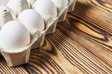 Karton kutu tavuk yumurta seti rustik ahşap masa üzerinde yatıyor. Metin için alan