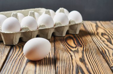 Karton kutu içinde set yakın bir yumurta rustik ahşap masa üzerinde yatıyor. Metin için alan