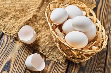 Kabukları yakınında tavuk yumurtası dolu talaş ile Sepet rustik ahşap masa üzerinde yatıyor