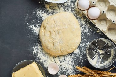 Farklı mutfak eşyaları ve malzemeler yakın un ile Hamur koyu beton masa üzerinde yatıyor. Pişirme işlemi. Kopya alanı. Üstte görüntü