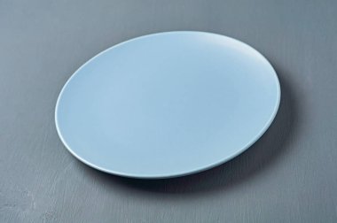 Mavi renk modern boş seramik plaka koyu beton arka plan üzerinde yatıyor