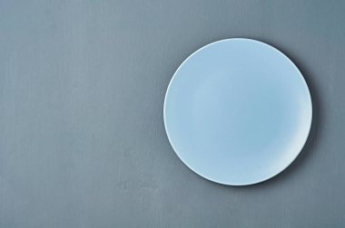 Mavi renk modern boş seramik plaka koyu beton arka plan üzerinde yatıyor. Metin için boşluk. Üstte görüntü