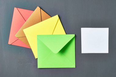 Yeşil açık kare zarf ın yanında boş beyaz kağıt levha eski çizik koyu beton yatıyor. Metin için boşluk. Üstte görüntü