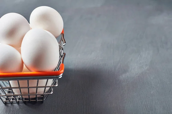 Market basket full of eggs lies on rustic wooden table. Space for text