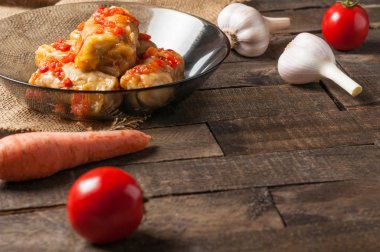 Çuvallama ve rustik ahşap masa üzerinde sebze yakın siyah cam tabakta pirinç ve et dolu domates soslu haşlanmış lahana rulo bir porsiyon