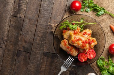 Çuvallama ve rustik ahşap masa üzerinde sebze yakın metal çatal ile siyah cam tabakta pirinç ve et dolu haşlanmış lahana rulo bir porsiyon