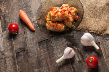 Çuvallama ve rustik ahşap masa üzerinde sebze yakın siyah cam tabakta pirinç ve et dolu domates soslu haşlanmış lahana rulo bir porsiyon