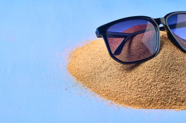 Siyah güneş gözlüğü ve mavi çizik beton üzerinde kuru kum yığını. Metin için alan