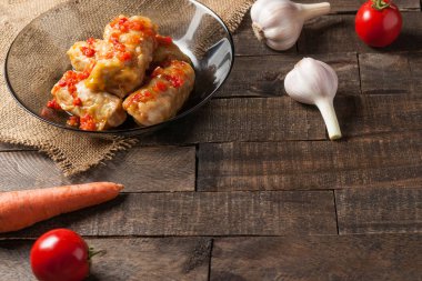 Çuvallama ve rustik ahşap masa üzerinde sebze yakın siyah cam tabakta pirinç ve et dolu domates soslu haşlanmış lahana rulo bir porsiyon