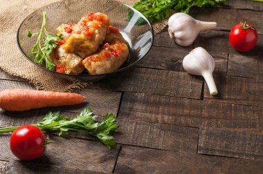 Çuvallama ve rustik ahşap masa üzerinde sebze yakın siyah cam tabakta pirinç ve et dolu domates soslu haşlanmış lahana rulo bir porsiyon