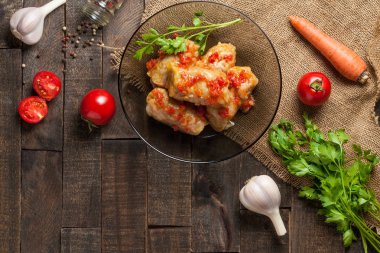 Çuvallama ve rustik ahşap masa üzerinde sebze yakın siyah cam tabakta pirinç ve et dolu domates soslu haşlanmış lahana rulo bir porsiyon