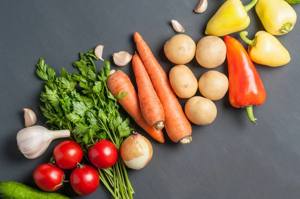 Farklı taze bütün olgun sebze seti koyu beton masa üzerinde yatıyor