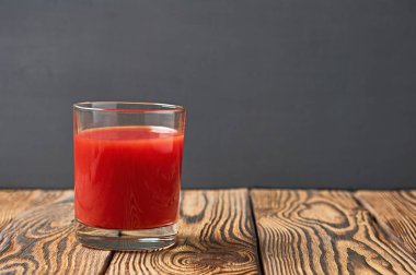 Bir bardak taze domates suyu eski ahşap masa üzerinde yatıyor. Metin için boşluk