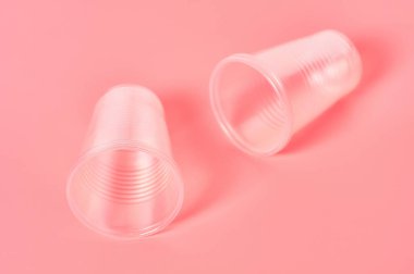 Pembe arka plana saçılmış tek kullanımlık plastik bardaklar. Piknik, parti ve diğer etkinliklerde tasarruf ortamı, ekoloji, eğlence kavramı