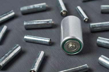 Koyu beton masaya farklı boyutlarda dağınık eski bataryalar. Geri dönüşüm konsepti. Çevreyi koru. Alternatif enerji