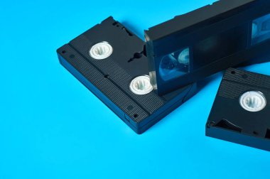 Dağıtılmış eski siyah plastik video kasetler mavi masanın üzerinde duruyor. 90 'ların konsepti. Boşluğu kopyala