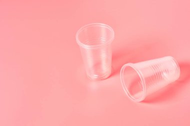 Pembe arka plana saçılmış tek kullanımlık plastik bardaklar. Çevreyi, ekolojiyi, piknik, parti ve diğer etkinlikleri kurtarma kavramı. Boşluğu kopyala
